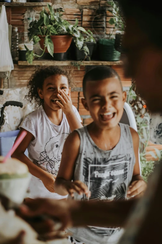 a couple of kids that are standing in a kitchen, pexels contest winner, brazil, group sit at table, earing a shirt laughing, outside