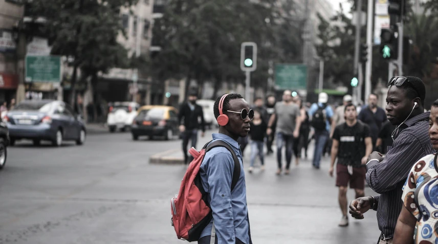 a group of people standing on the side of a street, an album cover, pexels contest winner, headphones on his head, a man wearing a backpack, mkbhd, turkey