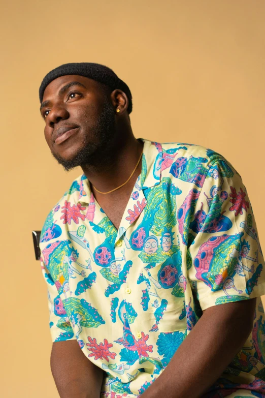 a man sitting on a stool wearing a colorful shirt, an album cover, inspired by Paul Georges, trending on pexels, big smirk, ( ( dark skin ) ), big floppa, sideways glance