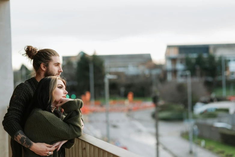 a man standing next to a woman on a balcony, by Lee Loughridge, unsplash, holding each other, looking off into the distance, college, pewdiepie selfie at a bridge