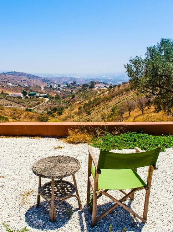 a couple of chairs sitting on top of a gravel field, by Julia Pishtar, pexels contest winner, renaissance, lots of oak and olive trees, green valley below, at the terrace, panoramic view