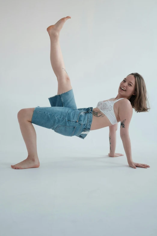a woman doing a handstand pose against a white background, by Jessie Algie, baggy jeans, wearing a tee shirt and combats, bixbite, sitting down casually