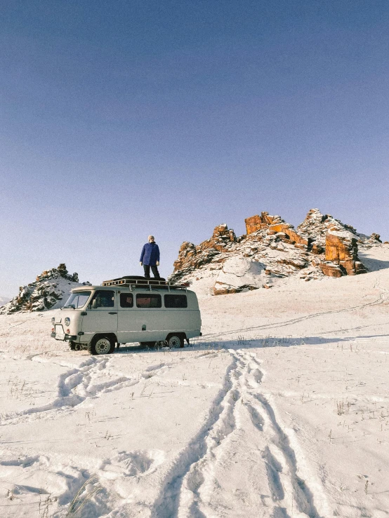 a man standing on top of a van in the snow, an album cover, inspired by Vasily Vereshchagin, pexels contest winner, rock formations, fuji superia, in the australian outback, 000 — википедия