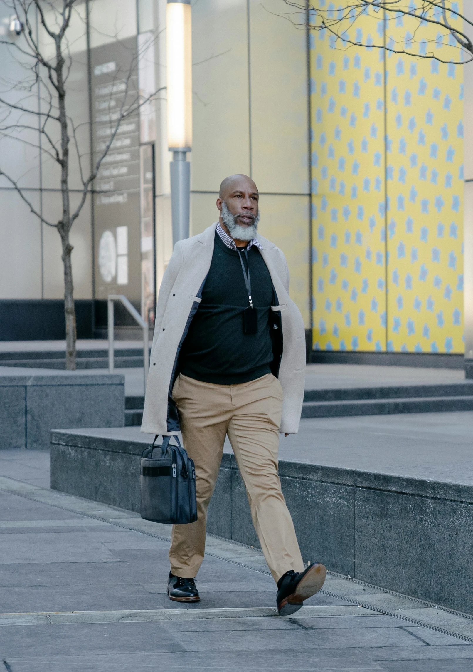 a man walking down a sidewalk carrying a briefcase, inspired by Charles Alston, grey trimmed beard, riyahd cassiem, at a mall, documentary still