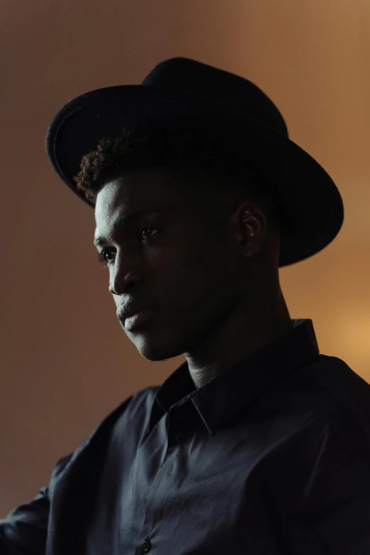 a close up of a person wearing a hat, by James Morris, black teenage boy, profile posing, standing in a dimly lit room, promotional image