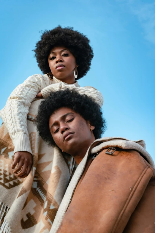 a woman sitting on top of a man's shoulders, trending on pexels, afrofuturism, roots and hay coat, beautiful gemini twins portrait, with afro, in a brown leather maxi jacket