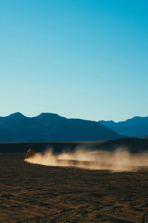 a person riding a dirt bike in the desert, unsplash contest winner, land art, new zealand, active volcano, late morning, extremely windy