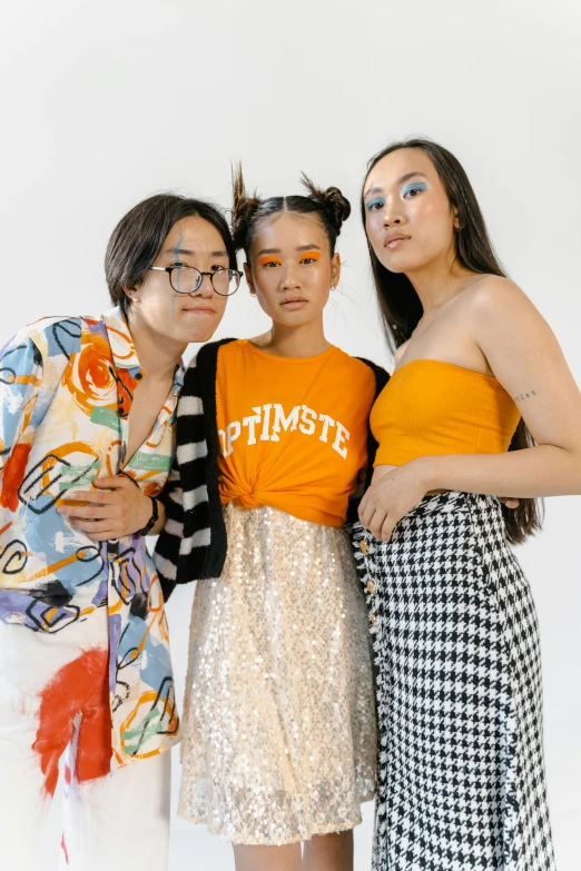 a group of three women standing next to each other, inspired by Ren Hang, trending on pexels, gutai group, asian man, modeling studio, left eye stripe, tilt and orange