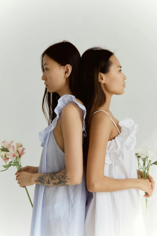 two women standing next to each other holding flowers, inspired by Cui Bai, trending on pexels, wearing a nightgown, on a pale background, ruffles, goop