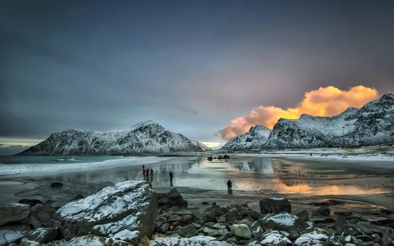 a group of people standing on top of a sandy beach, by Sebastian Spreng, pexels contest winner, snowy fjord, last light, fire and ice, a photo of the ocean