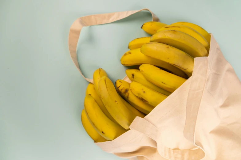 a bag full of bananas sitting on top of a table, light yellow, thumbnail, detail shot