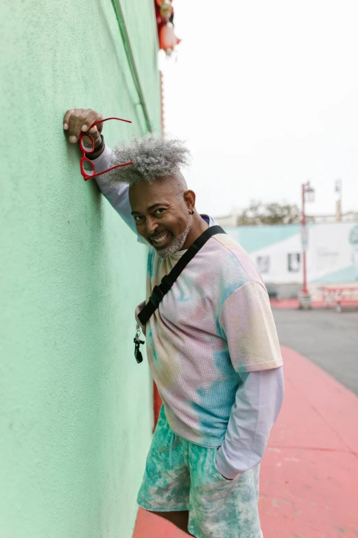 a man leaning against a wall on a skateboard, by Winona Nelson, rococo, wearing silver hair, ashteroth, rainbow accents, official photo