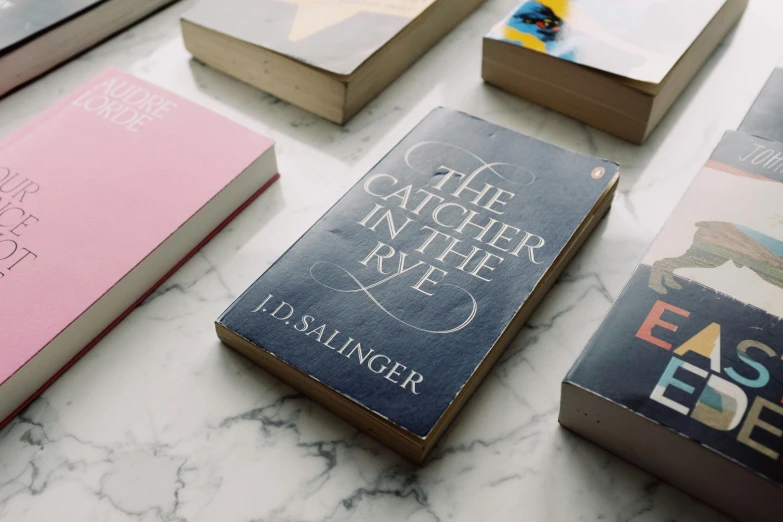 a bunch of books sitting on top of a table, inspired by Max Klinger, trending on unsplash, carrington, romance book cover style, catchlight in the eyes, engraved