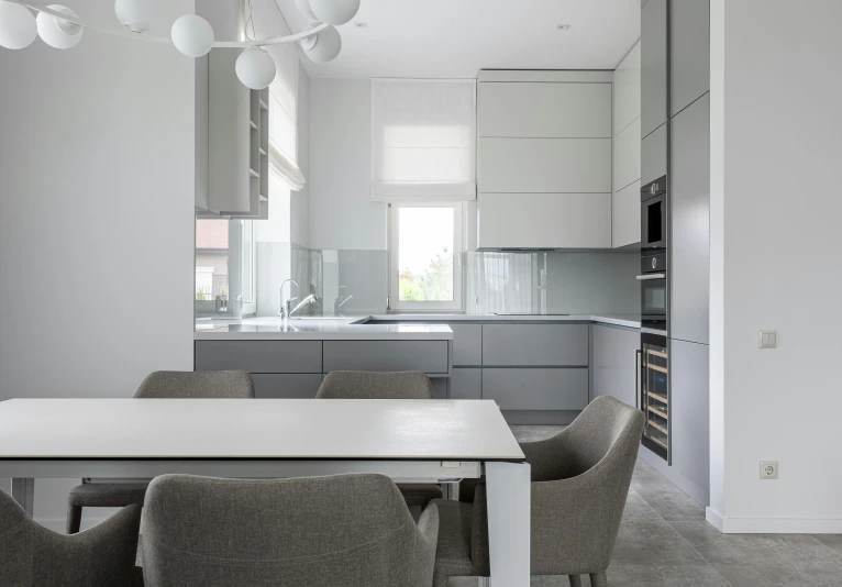 a white table and some chairs in a room, by Adam Marczyński, unsplash contest winner, light and space, luxury bespoke kitchen design, gray color, cupboards, flat grey