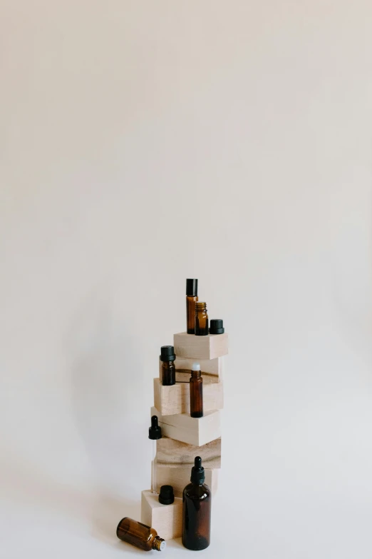 a stack of bottles sitting on top of a table, an abstract sculpture, by Jessie Algie, unsplash, carrying a bottle of perfume, on white background, made of wood, dwell