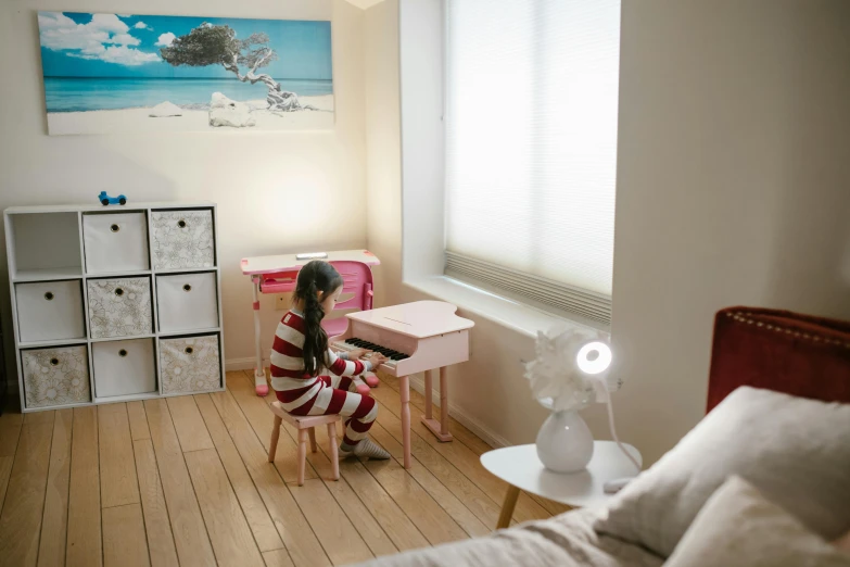 a little girl sitting on a chair in a room, inspired by Yamaguchi Kayo, unsplash, small and cosy student bedroom, gaming table, takada akemi, tactile buttons and lights