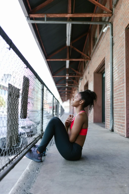 a woman sitting on the ground talking on a cell phone, pexels contest winner, athletic crossfit build, beautiful city black woman only, looking off into the distance, physical : tinyest midriff ever