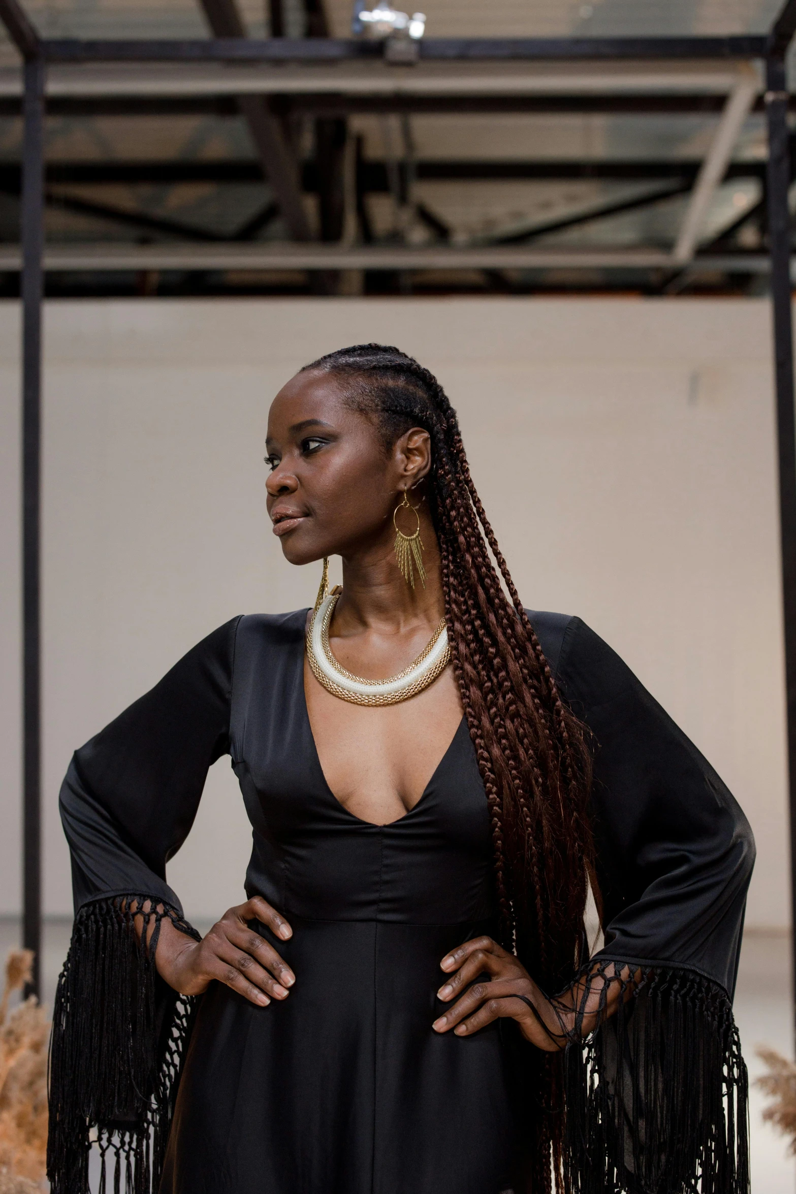 a woman in a black dress posing for a picture, inspired by Theo Constanté, pexels contest winner, afrofuturism, woman with braided brown hair, looking away from camera, lady kima, tall thin beautiful goddess