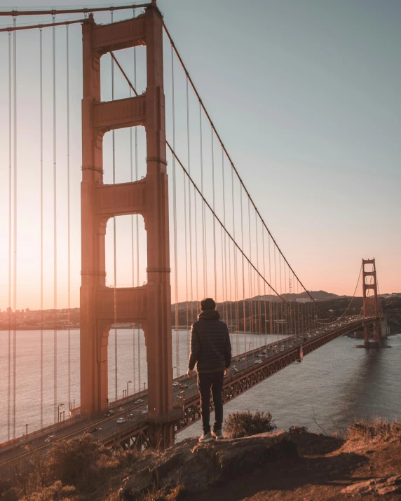 a person standing in front of the golden gate bridge, pexels contest winner, lgbtq, skyscrapers in the distance, trending on pintrest, a photo of a man