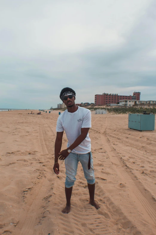 a man standing on top of a sandy beach, an album cover, trending on unsplash, graffiti, handsome hip hop young black man, new jersey, south african coast, slightly pixelated