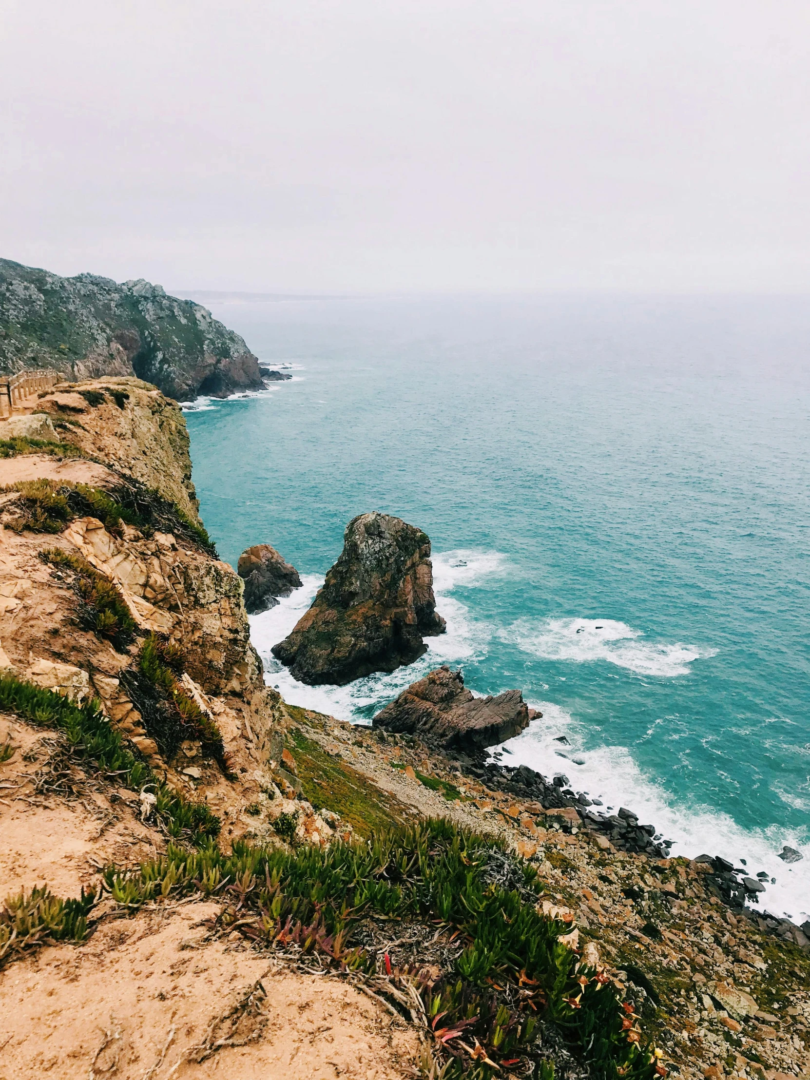 a man standing on top of a cliff next to the ocean, portugal, snapchat photo, slight overcast, slide show