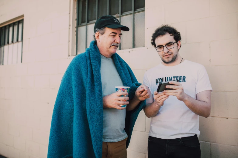 a couple of men standing next to each other, pexels contest winner, happening, looking at his phone, andy milonakis, grandfatherly, aussie baristas