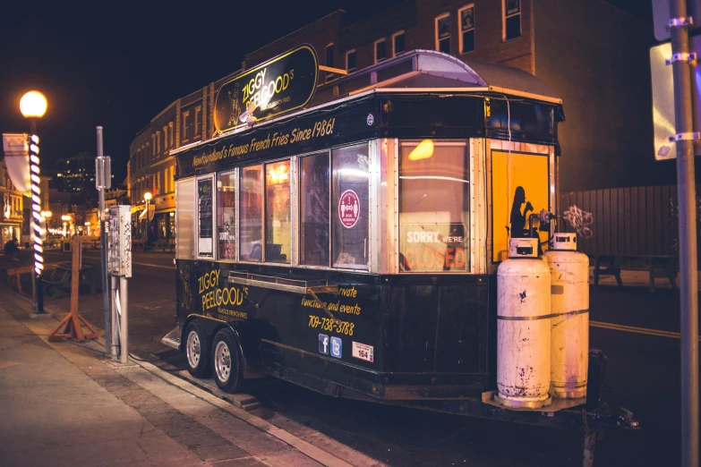 a trolley is parked on the side of the street, by Nick Fudge, unsplash, lyco art, regal fast food joint, at night time, black and yellow scheme, ebony rococo