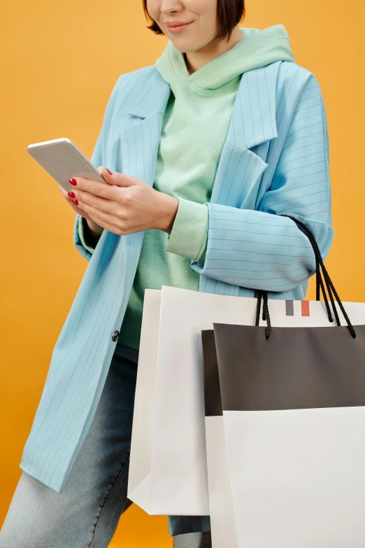 a woman holding shopping bags and looking at her phone, by Carey Morris, square, wearing a fancy jacket, plain background, istock