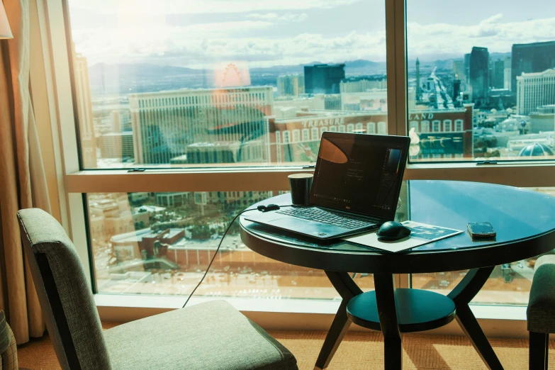 a laptop computer sitting on top of a glass table, by Robbie Trevino, unsplash, las vegas strip, floor to ceiling window, sitting on a mocha-colored table, thumbnail