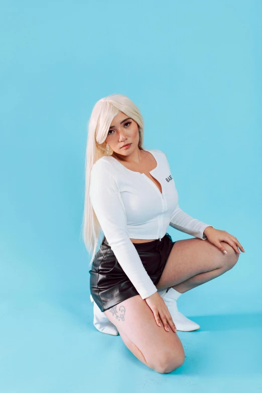 a woman sitting on the ground with her legs crossed, an album cover, inspired by Elsa Bleda, featured on reddit, renaissance, tifa lockhart with white hair, bra and shorts streetwear, professional cosplay, on a white table