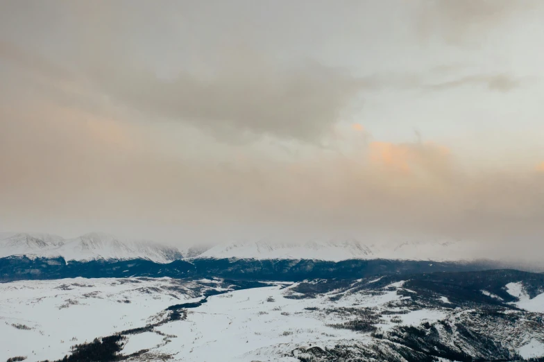 a man riding skis on top of a snow covered slope, trending on unsplash, visual art, storm clouds in the distance, distant mountains lights photo, “ aerial view of a mountain, wind river valley