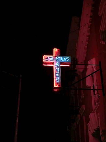 a neon cross hanging from the side of a building, by Matt Cavotta, pexels, renaissance, 2 5 6 x 2 5 6 pixels, annie liebowitz, jesus on cross, nightclub
