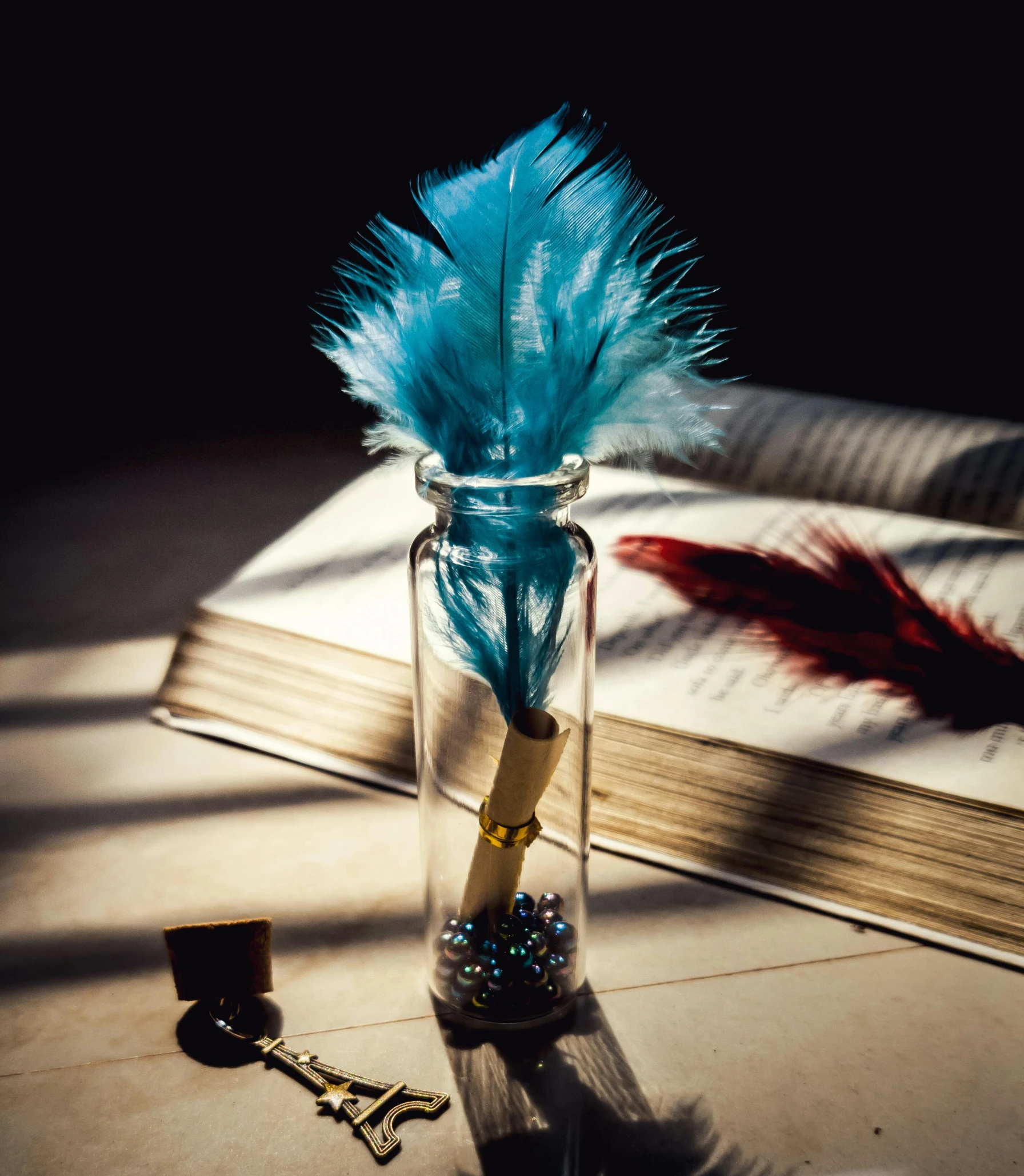 a book sitting on top of a table next to a feather, bottle, ((blue)), thumbnail, decoration