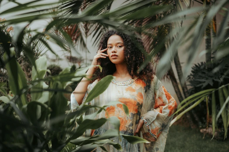 a woman standing in a garden talking on a cell phone, trending on pexels, afrofuturism, elegant tropical prints, young middle eastern woman, tessa thompson, floral clothes