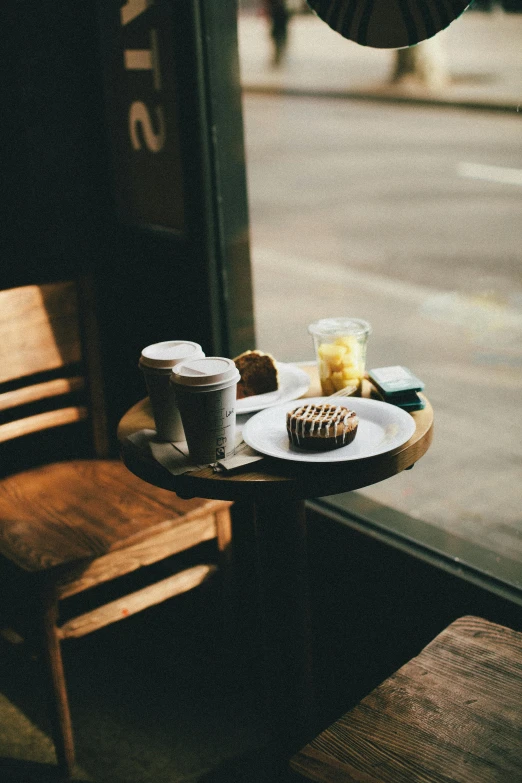 a table that has a plate of food on it, a still life, trending on unsplash, starbucks, window, bakery, multiple stories