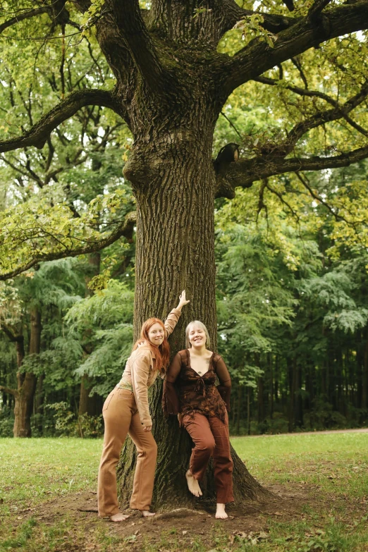 a couple of women standing next to a tree, an album cover, unsplash, renaissance, fauns, ((trees)), green and brown clothes, hannover