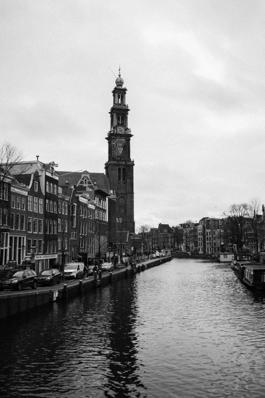 a black and white photo of a canal with a clock tower in the background, by Jacob Toorenvliet, in 2 0 1 5, built on a small, may)