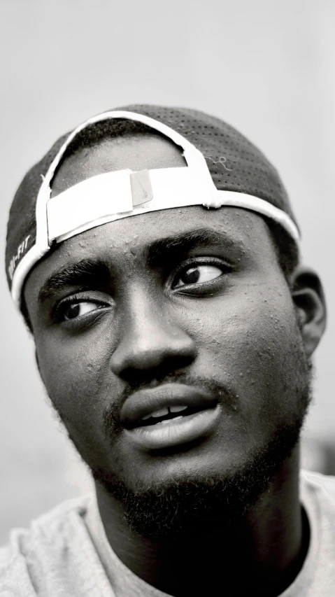 a black and white photo of a man with a bandage on his head, an album cover, by Chinwe Chukwuogo-Roy, trending on pexels, dada, smirking, jaylen brown, taken in the late 2010s, looking to his left