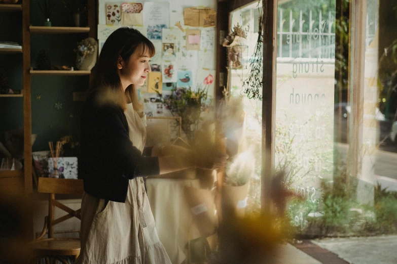 a woman standing in front of a window holding a teddy bear, pexels contest winner, visual art, flower shop scene, light coming from the windows, nishimiya shouko, in a coffee shop