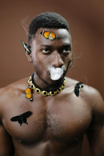 a close up of a person with a cigarette in his mouth, an album cover, inspired by Candido Bido, trending on pexels, afrofuturism, butterflies, barechest, made of insects, black teenage boy