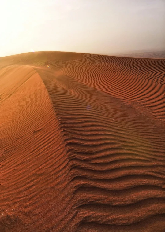 a person standing on top of a sand dune, in the middle of the desert, heat ripples, epic red - orange sunlight, dubai