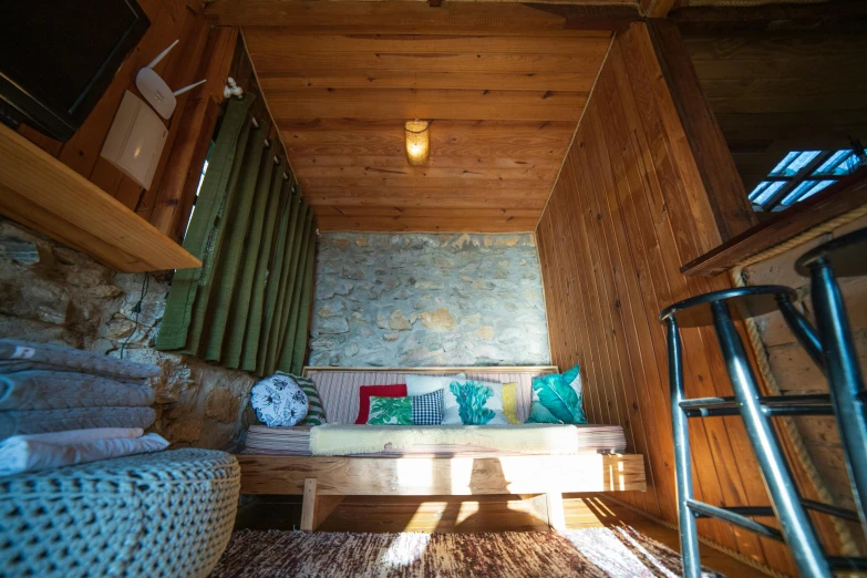 a couch sitting inside of a living room next to a window, hurufiyya, pine treehouse, profile image, interior of a mountain hut, tourist photo