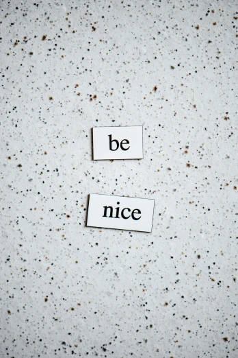 a piece of paper with the words be nice written on it, by Niko Henrichon, trending on unsplash, made of all white ceramic tiles, magnetic, taken on iphone 14 pro, alessio albi