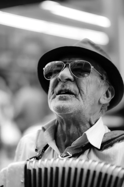 a black and white photo of an old man playing an accordion, a black and white photo, inspired by Sergio Larraín, pexels contest winner, photorealism, wearing sunglasses and a hat, looking upwards, portrait photo of an old man, profile image