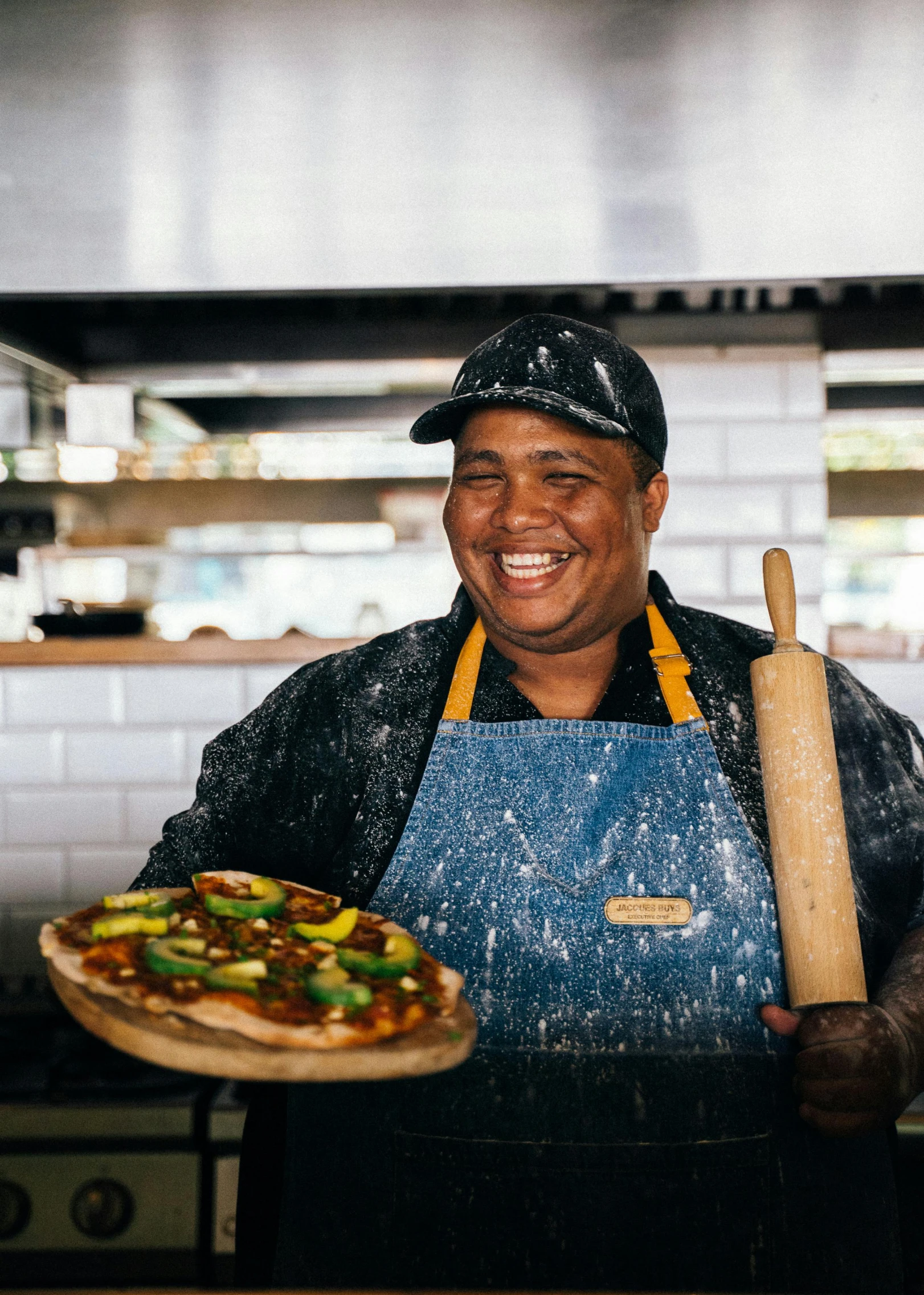 a man holding a pizza in a kitchen, a portrait, pexels contest winner, smiling spartan, ethiopian, thumbnail, woodfired