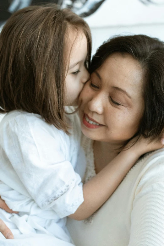 a woman kissing a little girl on the cheek, inspired by Cui Bai, pexels contest winner, incoherents, soft texture, profile image, asian woman, hugging each other