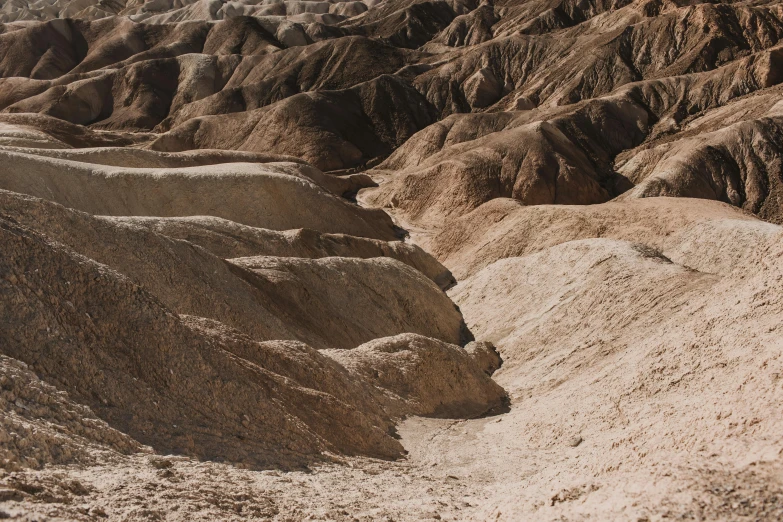 a man riding a skateboard on top of a sandy hill, unsplash contest winner, les nabis, shiny layered geological strata, muted brown, thumbnail, the middle of a valley