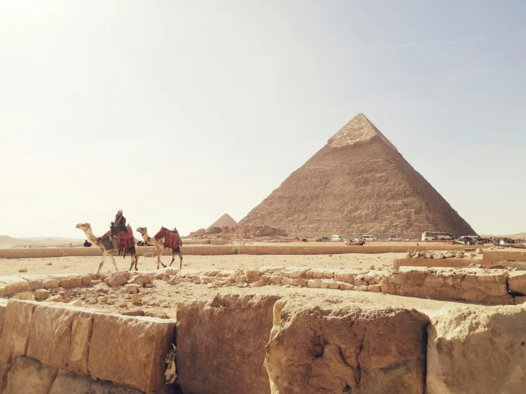 a couple of people riding on the backs of camels, egyptian art, pexels contest winner, ancient megastructure pyramid, photo on iphone, 🦩🪐🐞👩🏻🦳, buildings carved out of stone