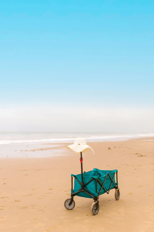 a cart sitting on top of a beach next to the ocean, single chair, standing with a parasol, facing away, south african coast