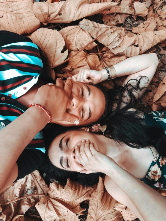 a couple of people laying on top of a pile of leaves, by Robbie Trevino, in love selfie, asian, profile image, close up portrait photo